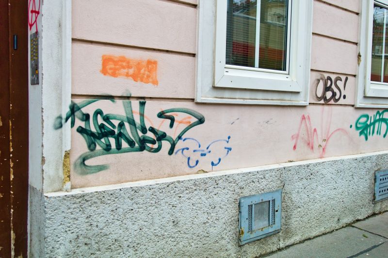 Mit Graffitis und Aufschriften verunreinigte Mauer eines Wohnhauses. Verschmutzung von Eigentum
