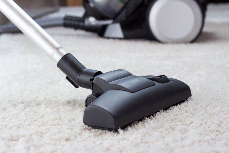 35808269 - close up of the head of a modern vacuum cleaner being used while vacuuming a thick pile carpet white